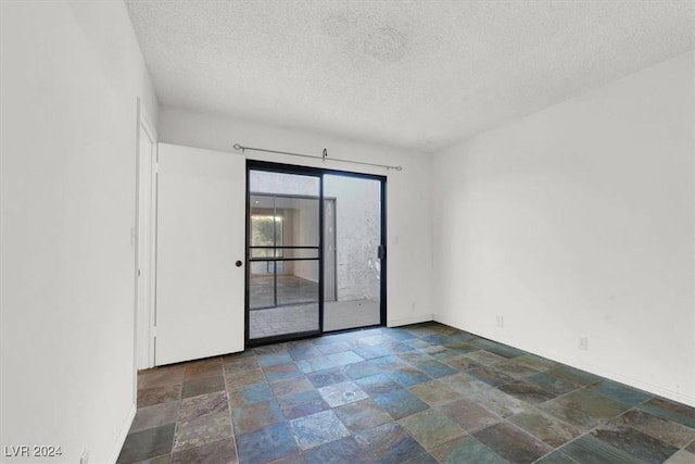 spare room with stone finish floor and a textured ceiling