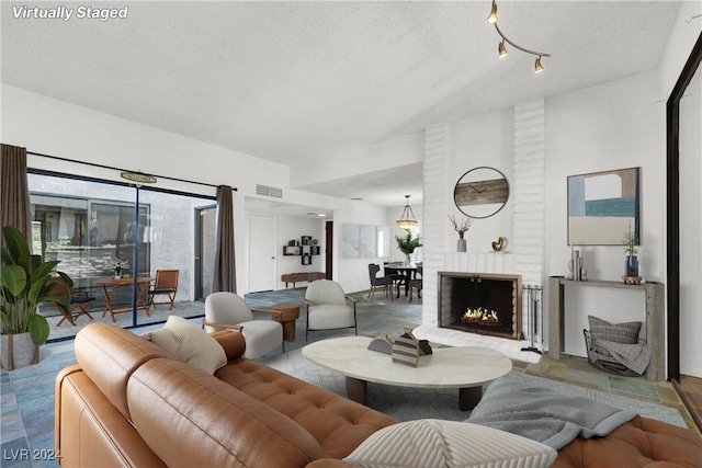 living room with a healthy amount of sunlight, visible vents, a fireplace, and a textured ceiling