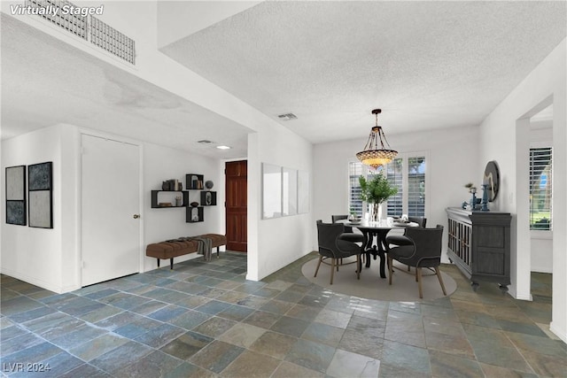 dining area with baseboards, visible vents, a textured ceiling, and stone tile floors