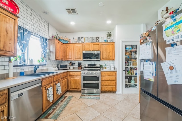 kitchen with light tile patterned flooring, backsplash, stainless steel appliances, and sink