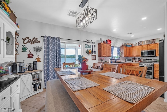 dining area with a notable chandelier, light tile patterned floors, and sink