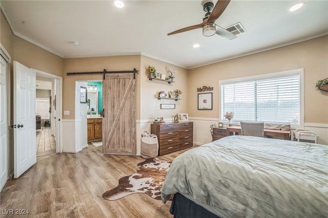 bedroom featuring ensuite bath, ceiling fan, crown molding, a barn door, and light hardwood / wood-style flooring