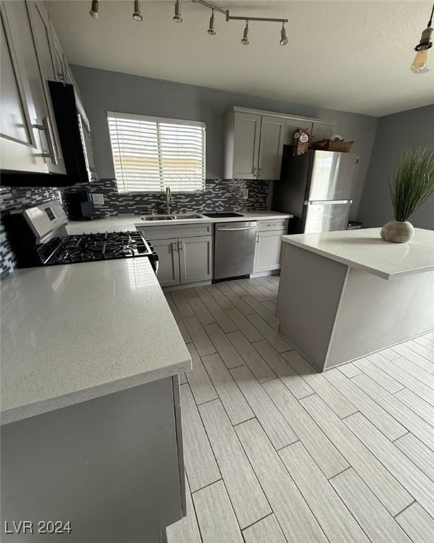 kitchen featuring sink, stainless steel appliances, a textured ceiling, decorative backsplash, and a kitchen island