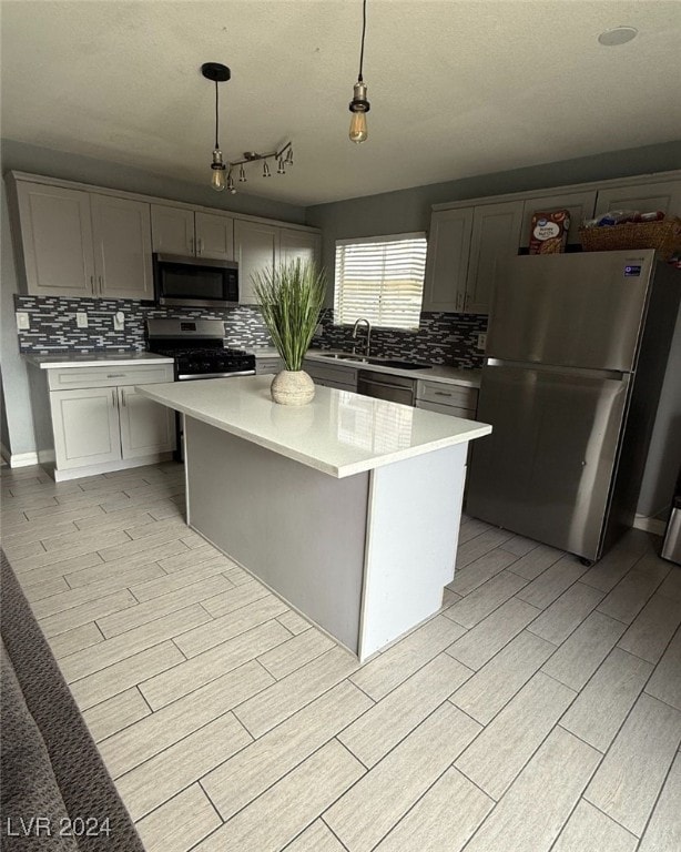 kitchen featuring gray cabinetry, a center island, backsplash, decorative light fixtures, and stainless steel appliances