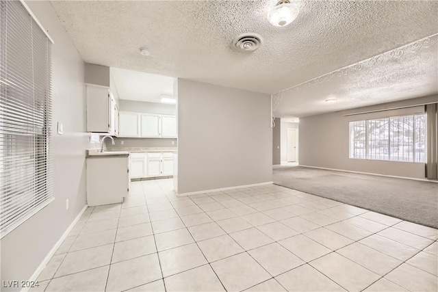 interior space featuring a textured ceiling, light colored carpet, and sink