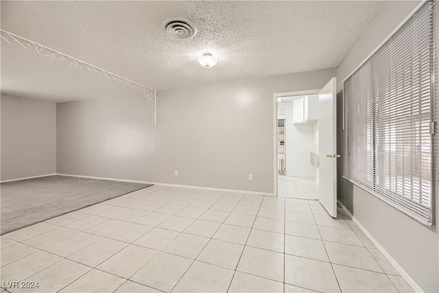 empty room featuring light tile patterned floors and a textured ceiling