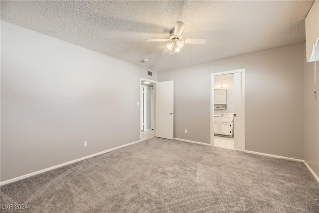 unfurnished bedroom with ceiling fan, light colored carpet, a textured ceiling, and connected bathroom