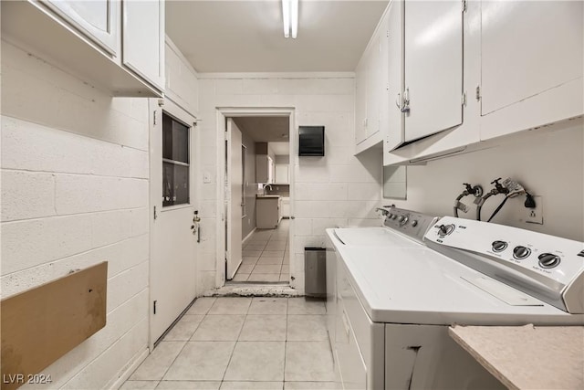 washroom with cabinets, sink, washing machine and clothes dryer, and light tile patterned flooring