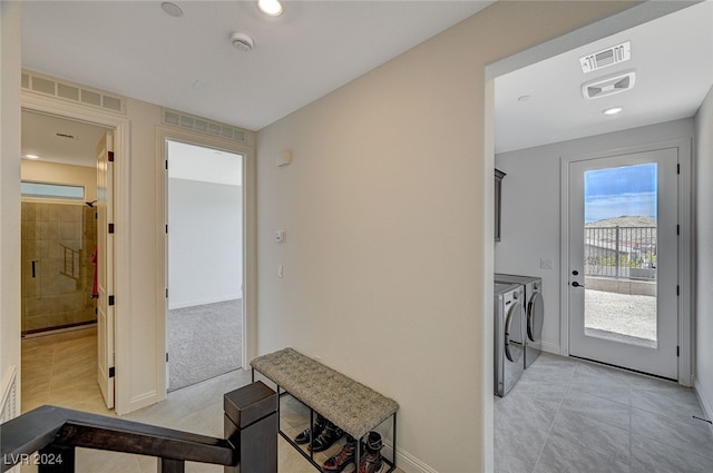 hallway featuring washer and dryer and light tile patterned floors