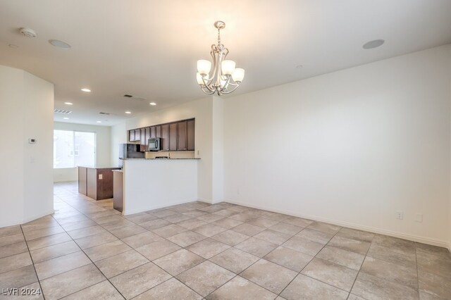 interior space with dark brown cabinets, decorative light fixtures, a notable chandelier, and light tile patterned flooring