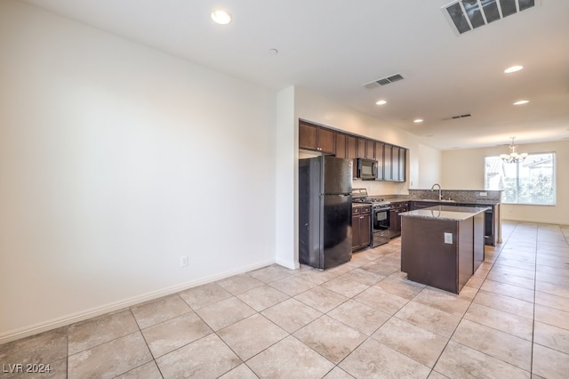 kitchen with an inviting chandelier, black fridge, sink, gas stove, and dark brown cabinetry