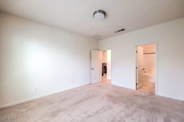 unfurnished bedroom featuring connected bathroom and light colored carpet