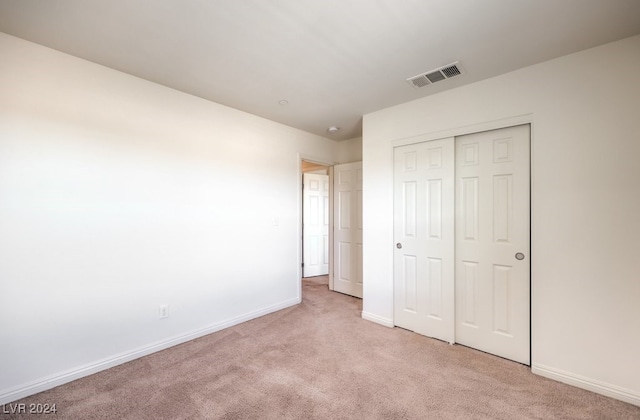 unfurnished bedroom with light carpet and a closet