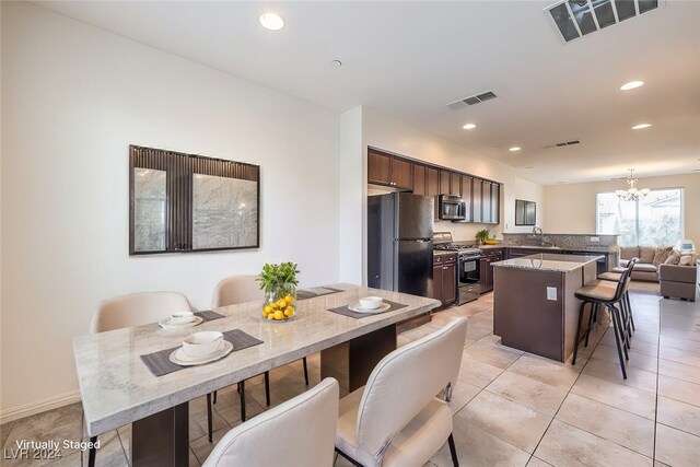 kitchen with kitchen peninsula, a kitchen breakfast bar, stainless steel appliances, sink, and a chandelier