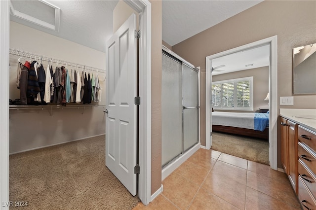 bathroom featuring a textured ceiling, vanity, tile patterned floors, and a shower with shower door