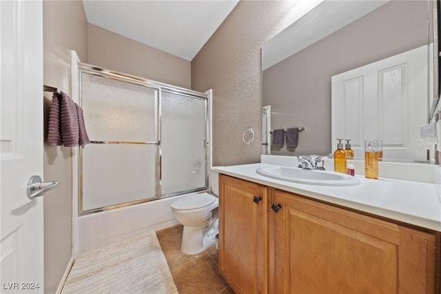 full bathroom featuring shower / bath combination with glass door, vanity, tile patterned flooring, and toilet