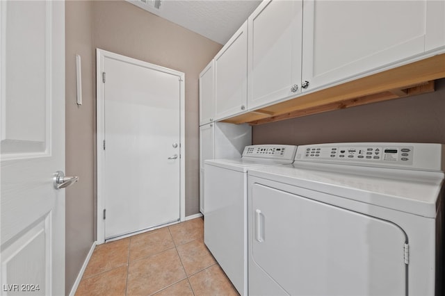 washroom featuring washer and dryer, light tile patterned flooring, cabinets, and a textured ceiling