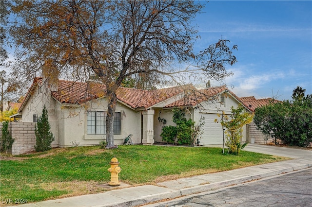 mediterranean / spanish-style house with a garage and a front lawn