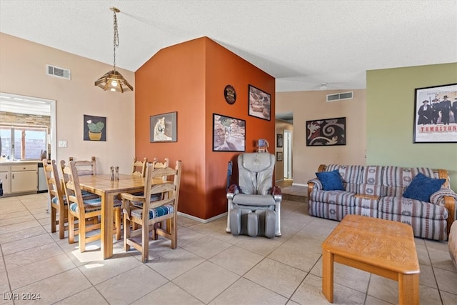 tiled dining area with a textured ceiling and lofted ceiling