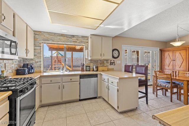 kitchen with a wealth of natural light, kitchen peninsula, a textured ceiling, and appliances with stainless steel finishes