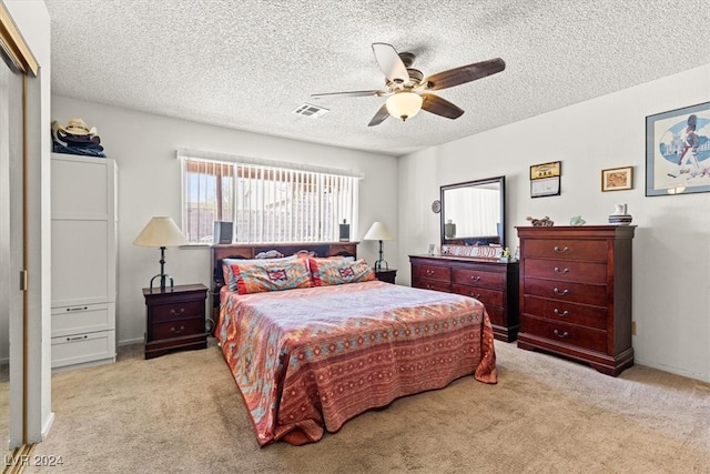 carpeted bedroom with ceiling fan and a textured ceiling