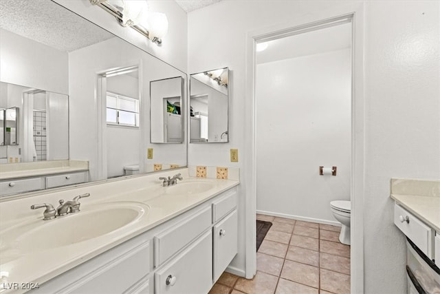 bathroom with tile patterned floors, vanity, a textured ceiling, and toilet