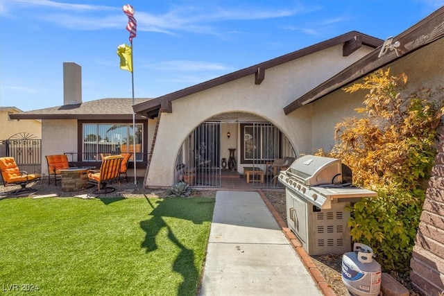 back of house with a lawn, a patio area, and an outdoor fire pit