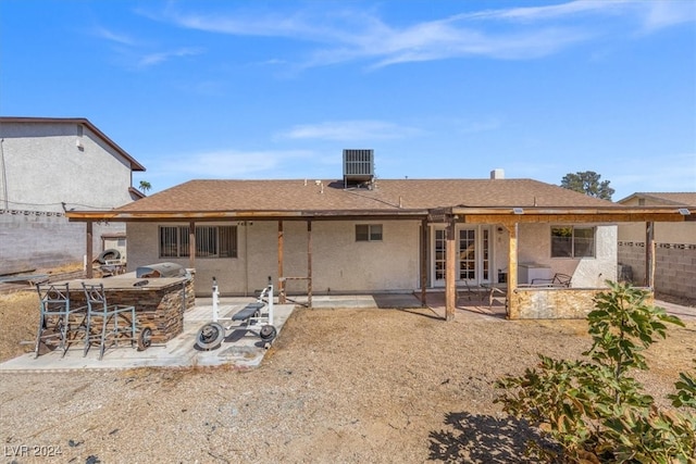 rear view of property featuring exterior kitchen, a patio area, central air condition unit, and an outdoor bar