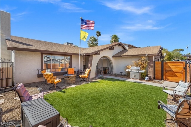 rear view of house with a fire pit and a lawn