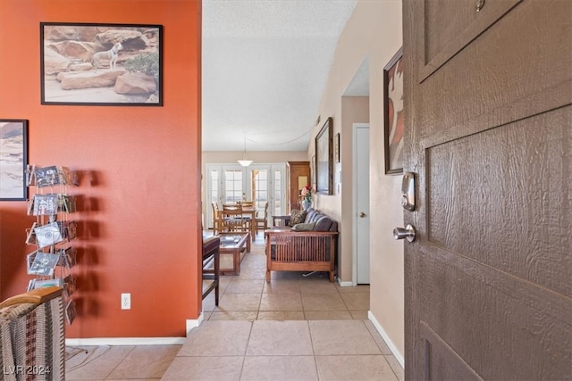 hall featuring light tile patterned floors and a textured ceiling