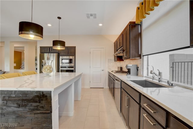 kitchen with backsplash, sink, appliances with stainless steel finishes, decorative light fixtures, and a kitchen island