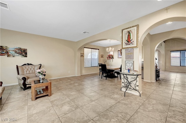 interior space with light tile patterned flooring and an inviting chandelier