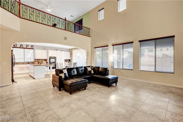 tiled living room featuring ceiling fan and a towering ceiling