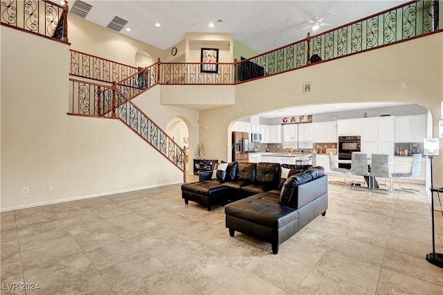 living room with a towering ceiling and ceiling fan