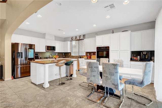 kitchen featuring white cabinets, a center island, stainless steel appliances, and tasteful backsplash