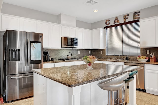 kitchen with white cabinets, a center island, dark stone countertops, and stainless steel appliances