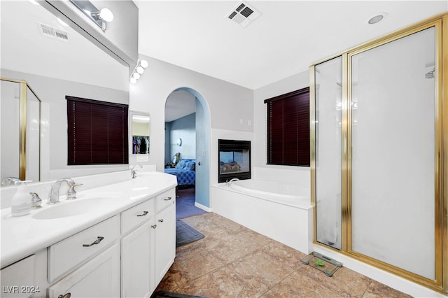 bathroom featuring a multi sided fireplace, vanity, tile patterned flooring, and plus walk in shower