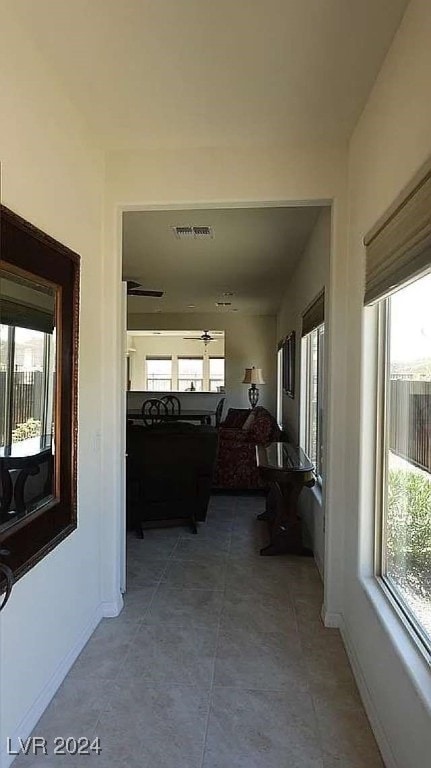 hall featuring light tile patterned floors and a healthy amount of sunlight