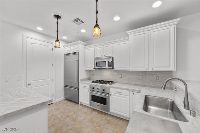 kitchen with pendant lighting, backsplash, sink, white cabinetry, and stainless steel appliances