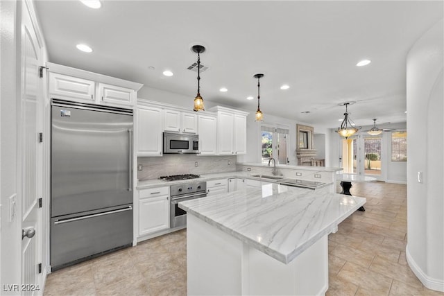 kitchen with a wealth of natural light, pendant lighting, white cabinets, and stainless steel appliances