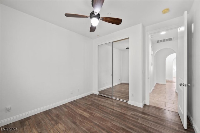 unfurnished bedroom with ceiling fan, a closet, and dark wood-type flooring