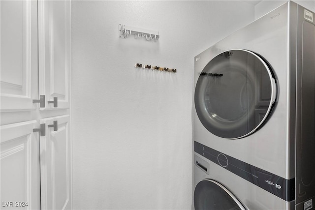 clothes washing area with cabinets and stacked washer and dryer