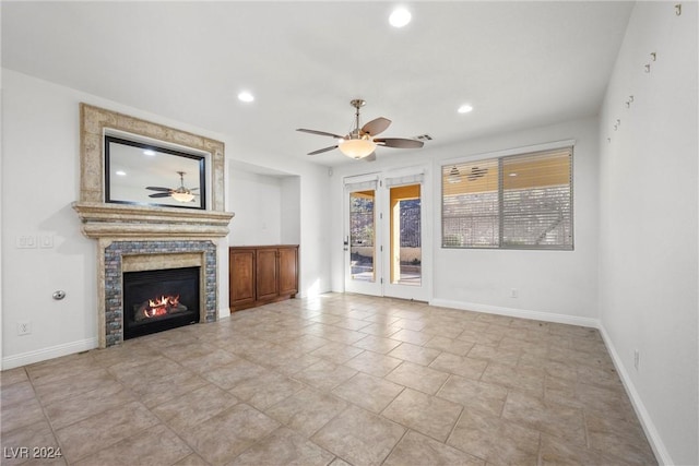 unfurnished living room featuring ceiling fan and a tiled fireplace