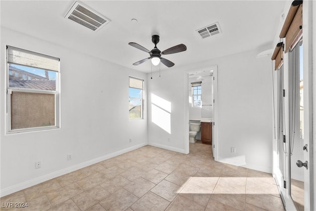 unfurnished bedroom featuring ensuite bathroom, ceiling fan, and light tile patterned flooring