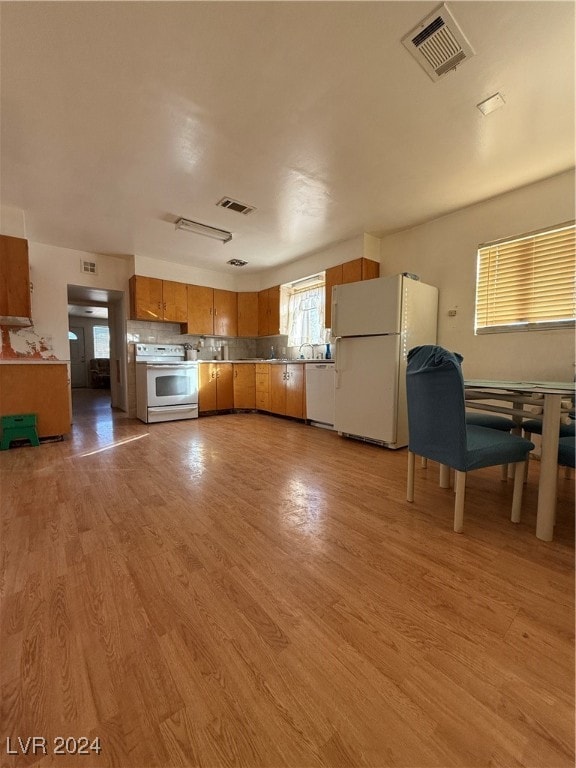 kitchen featuring light wood-type flooring, white appliances, and tasteful backsplash