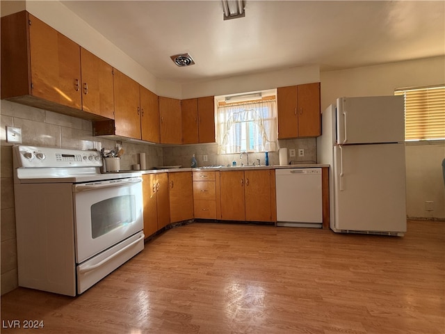 kitchen with light hardwood / wood-style floors, white appliances, and tasteful backsplash