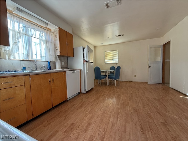 kitchen with decorative backsplash, sink, light hardwood / wood-style floors, and white appliances