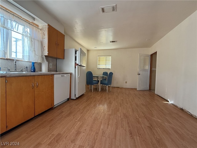 kitchen featuring white dishwasher, tasteful backsplash, sink, and light hardwood / wood-style flooring