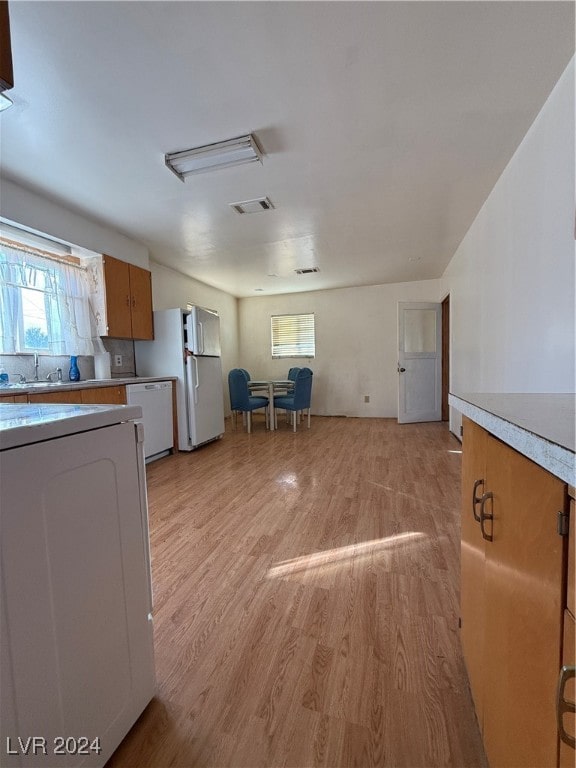 kitchen with white appliances, light hardwood / wood-style floors, and sink