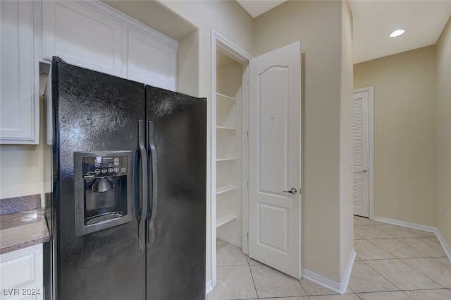 kitchen with white cabinetry, black refrigerator with ice dispenser, and light tile patterned floors